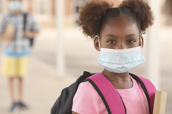 Young girl wearing a surgical mask at school.